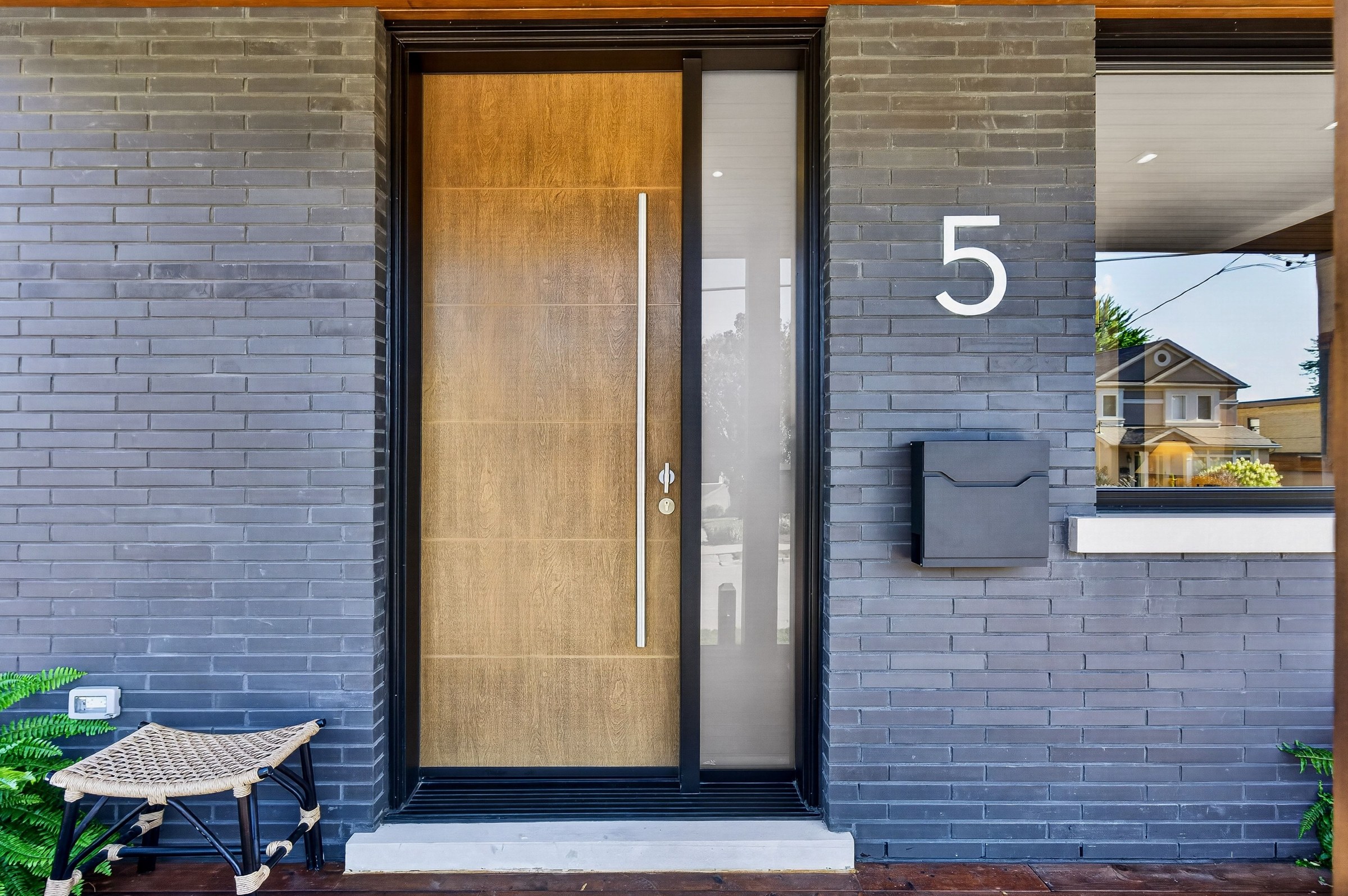 Wood front door and the number five set against dark brick