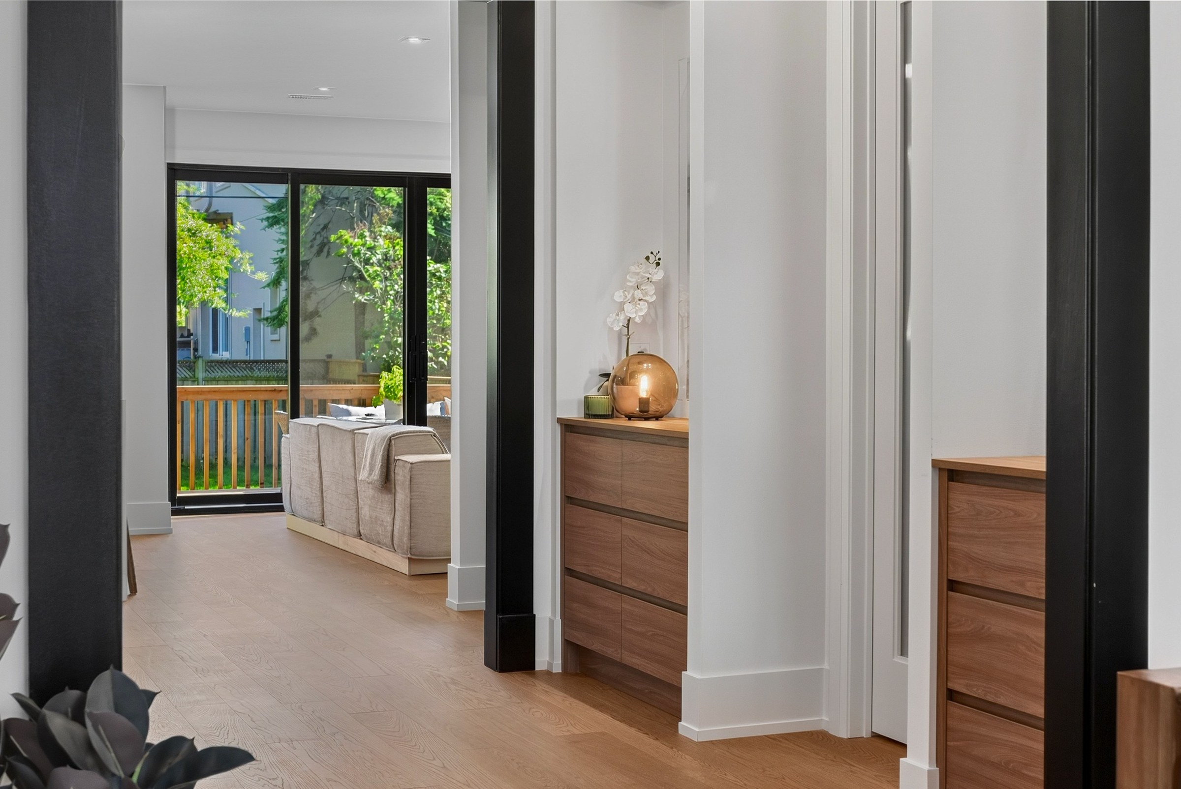 Layered dark door frames lead toward the sunlit living room