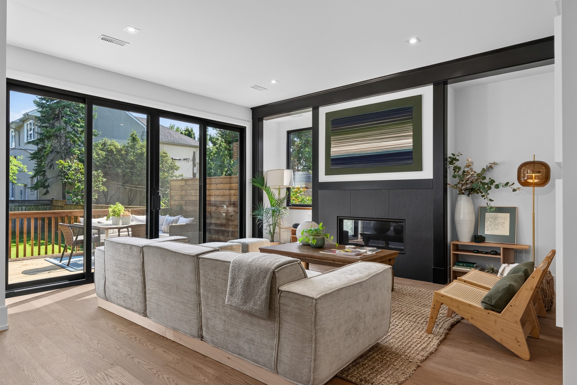 Daylit living room with dark fireplace framing and glass doors to the deck