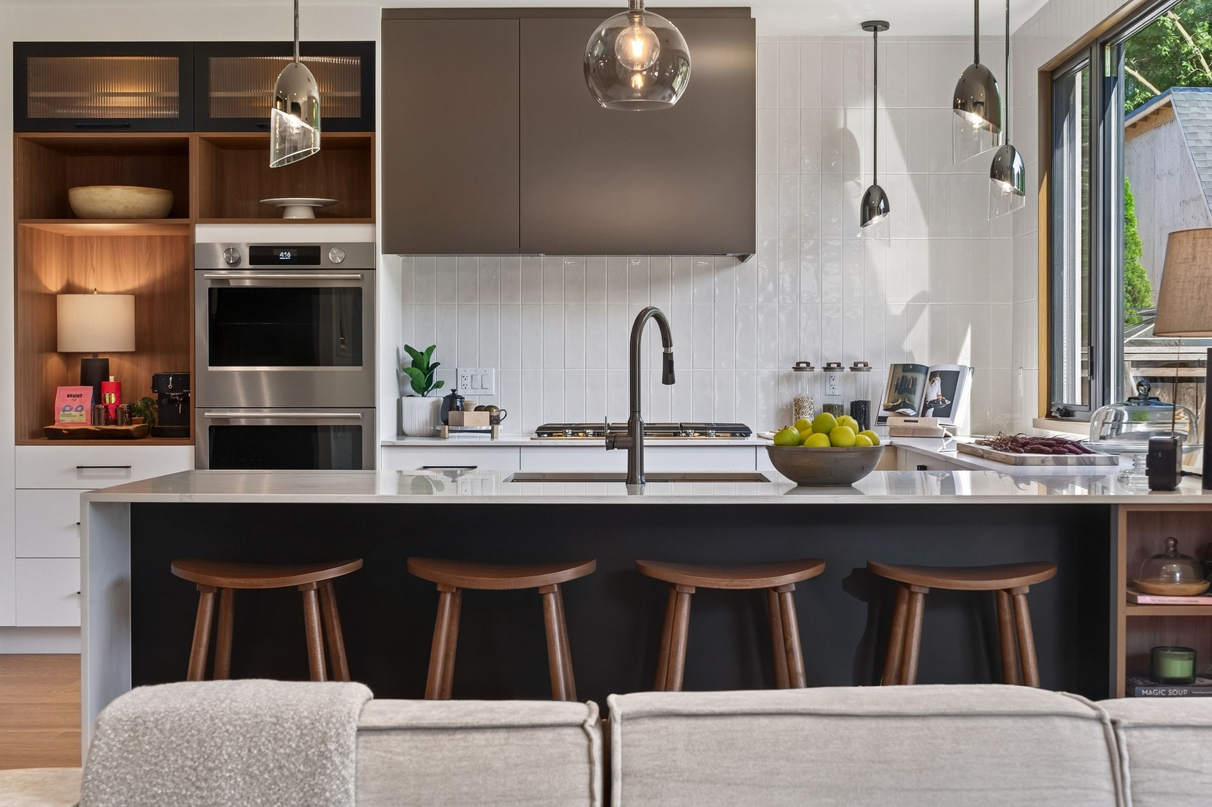 Kitchen counter with four wood stools, pendant lights and warm cabinetry