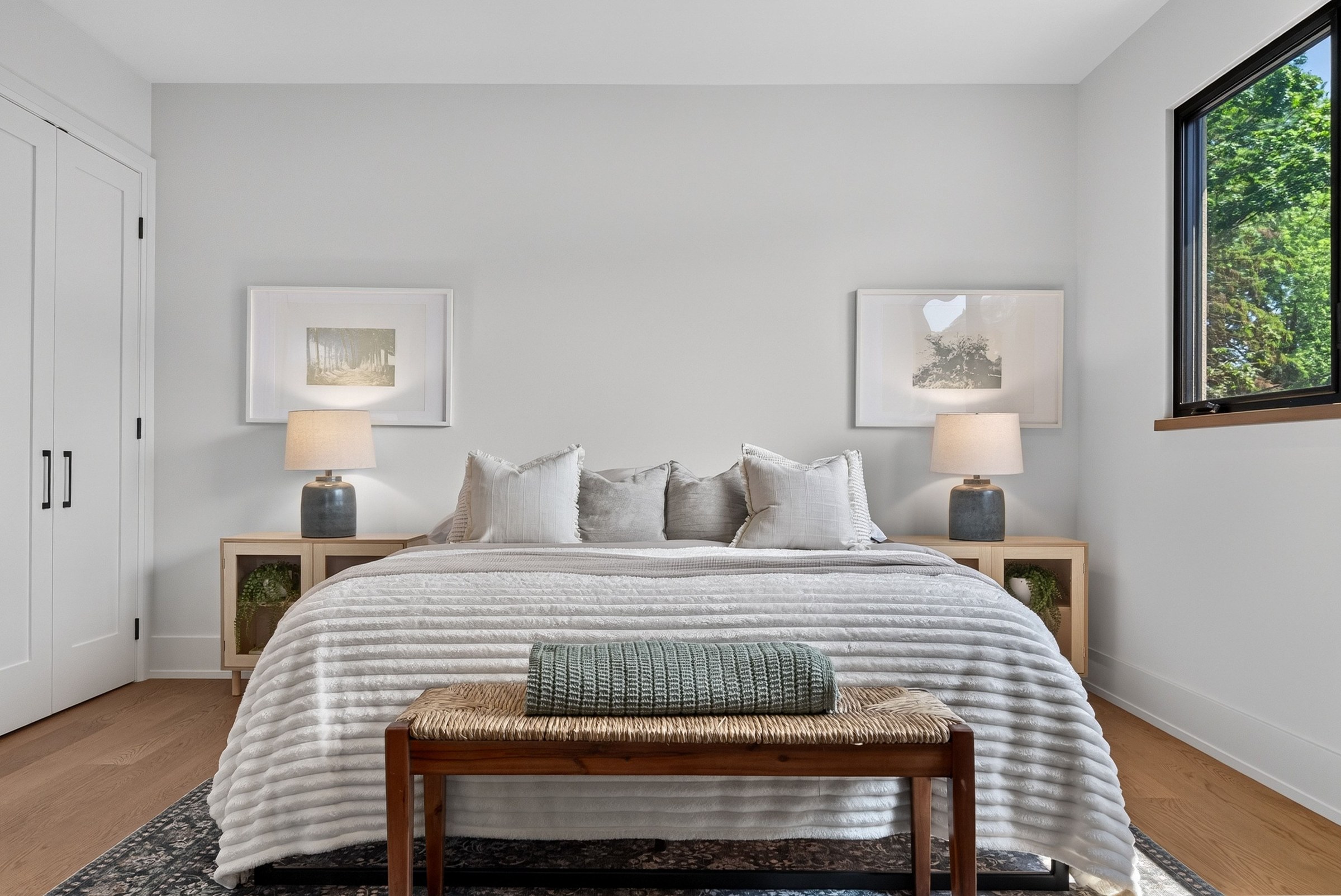 Calm bedroom with layered white bedding and daylight through a large window