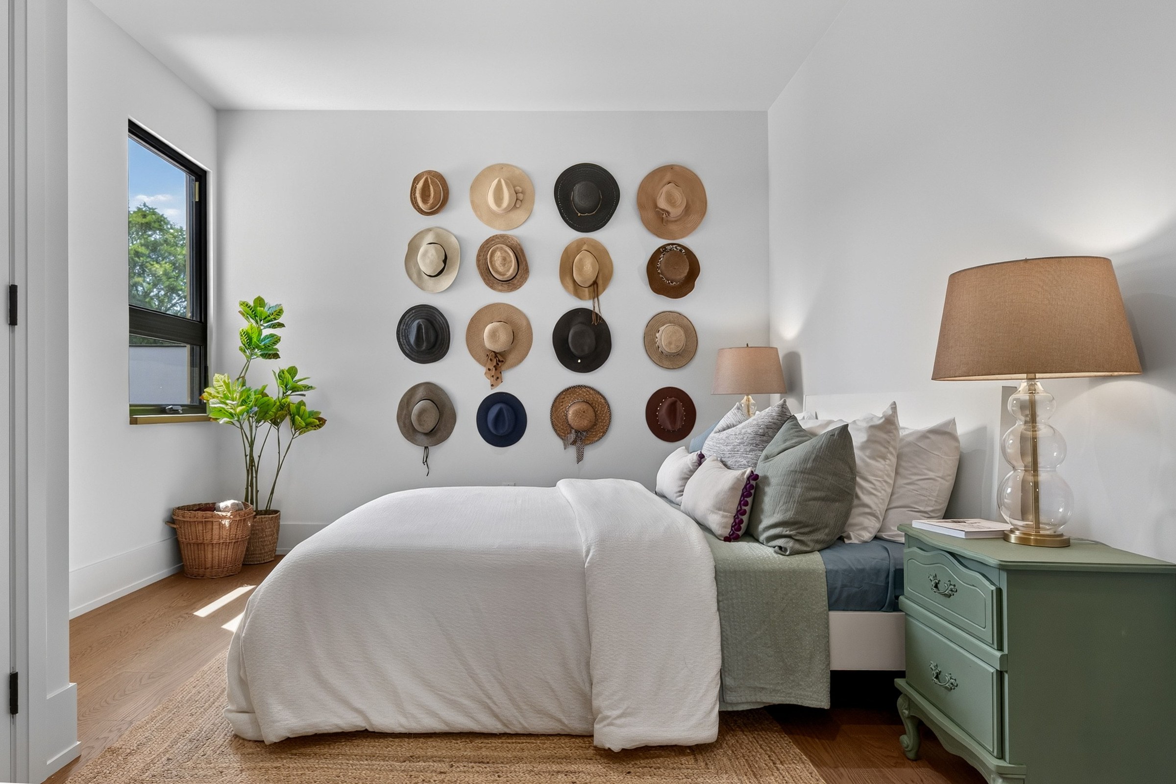 Sunlit bedroom with a collection of hats and a green bedside cabinet